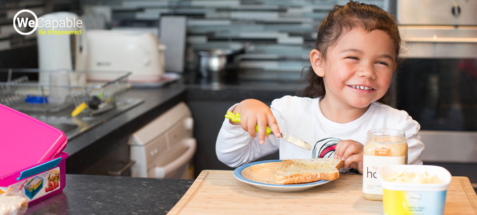 a girl with visual impairment smiling and buttering the toast